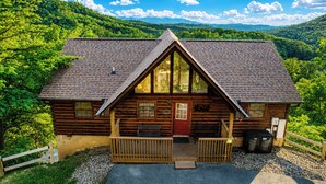 A log cabin with a red door, wooden porch, and a view of the surrounding forest. - 🏔️Private Sunsets🌅 Sunset Views, Hot Tub & Indoor Pool, near Dollywood (Sevierville)