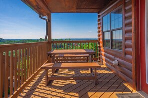 Une terrasse en bois avec une table et des bancs, offrant une vue sur un paysage boisé.