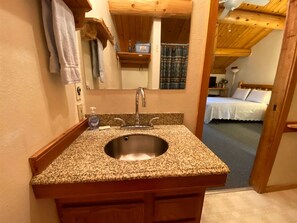 A bathroom with a granite countertop sink, a mirror, and a towel hanging on the wall. - Sleeping Wolf Studio w/ ski trail & river access, pool/hot tub (Winthrop)