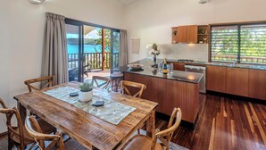 A modern kitchen with wooden cabinets, a central island, and a dining area with a wooden table and chairs.