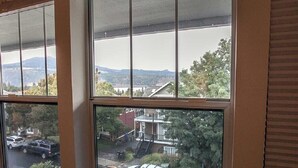 Vista a través de una ventana que muestra un barrio residencial, con casas y coches aparcados.