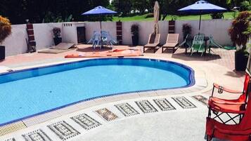 Relax by the clear pool surrounded by a deck, lounge chairs, and umbrellas.