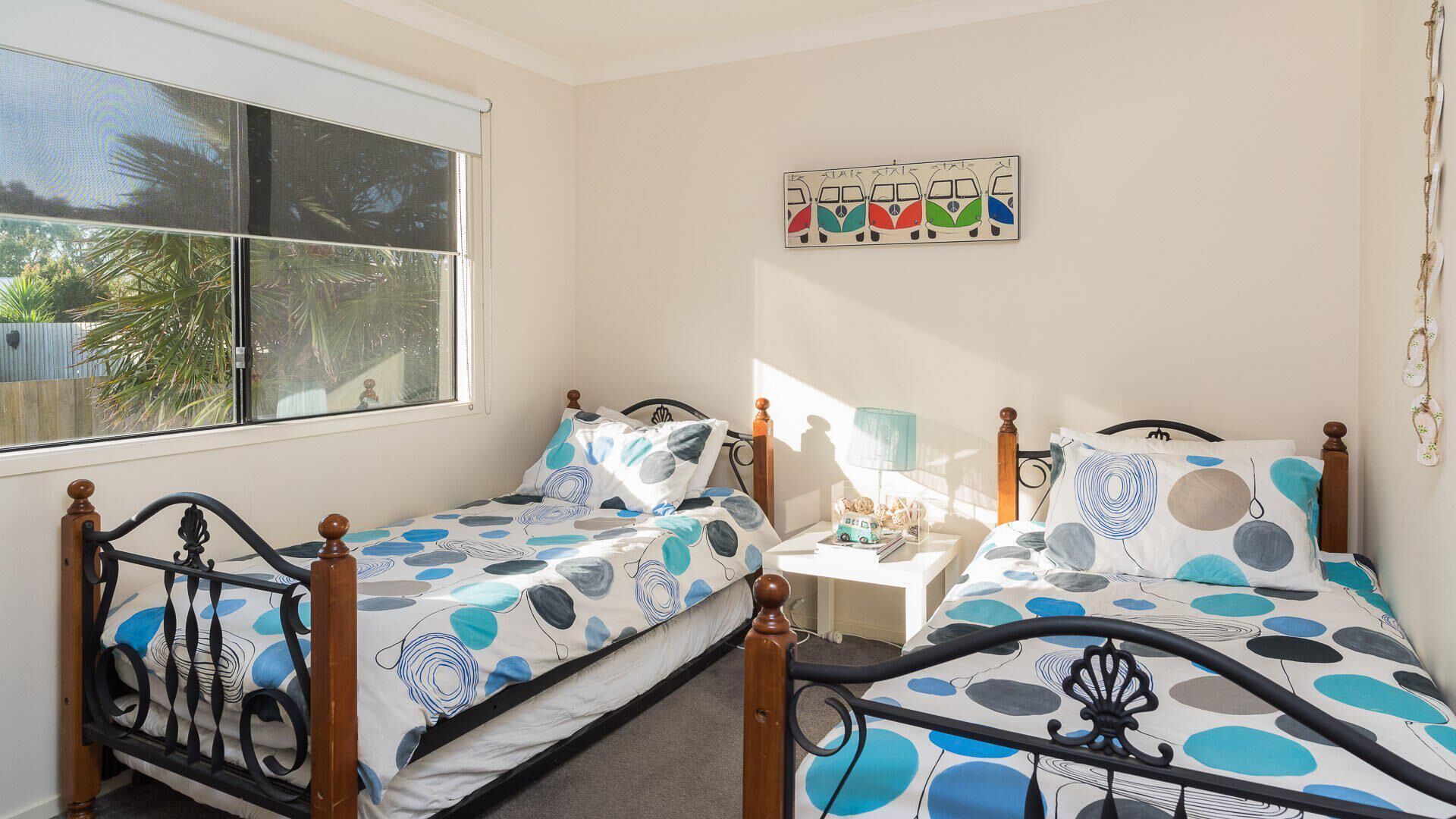 A room with two beds, a small table, and a window.