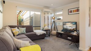 A living room with a sofa, a television, and a small table with decorative items.