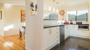A modern kitchen with white cabinets, a stainless steel dishwasher, a red toaster, and a microwave.