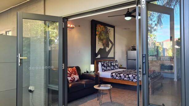 A modern bedroom with a bed, a sofa, a small table, and a ceiling fan.