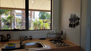 A kitchen with a large window, a sink, a stove, and a knife rack.