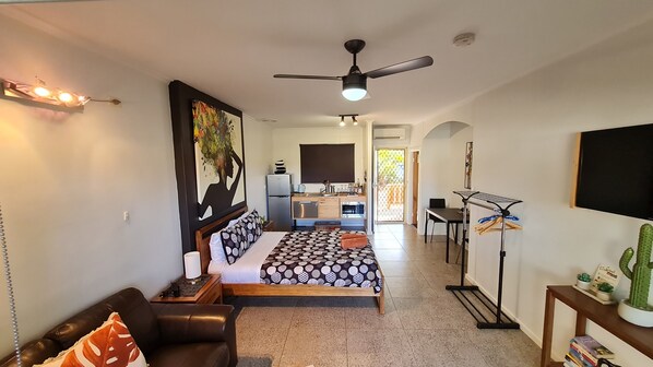 Una habitación de hotel moderna con cama, escritorio, kitchenette y comedor.