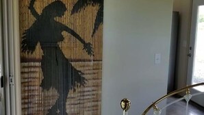A room with a bed, a bamboo screen with a silhouette, and a door.