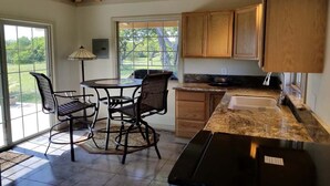 A kitchen with a dining area, wooden cabinets, a sink, and a large window.