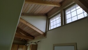 A room with a sloped wooden ceiling, a window with a grid pattern, and wooden cabinets.