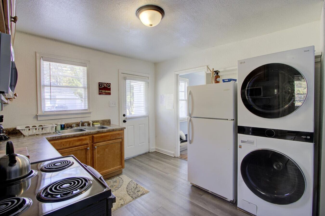 A compact kitchen with a stove, sink, and a large appliance that appears to be a washer and dryer.
