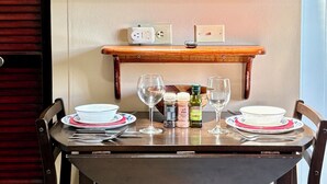 Een eettafel met stoelen, een televisie erboven en een plank met een stopcontact.