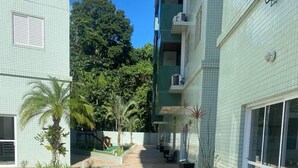 A courtyard with a tiled floor, potted plants, and a bench. - Apt-207 in Comfortable Condominium 350m from the beach W/Air cond (Praia Grande)