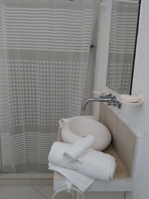 Chuveiro, toalhas de banho, sabonete, papel higiênico