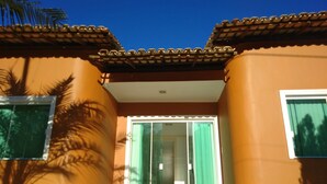 A building entrance with a glass door, a tiled roof, and a palm tree shadow. - BLACK FRIDAY FEBRUARY. Beautiful duplex house, Ilhéus-Bahia, Olivença, Cond.  (Ilheus)