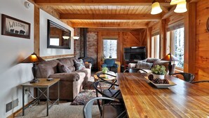 A cozy cabin interior with a wooden ceiling, a fireplace, a television, and a dining area. - Killington Cabin: Right Unit - Sleeps 10 in 4 BR, 2 BA Cozy Escape (Killington)