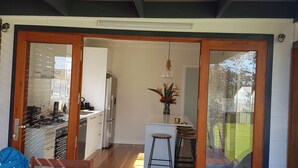 A modern kitchen with a dining area, wooden flooring, and a view of the backyard.