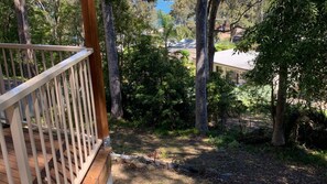 Une terrasse en bois offrant une vue sur une maison entourée d’une forêt dense.