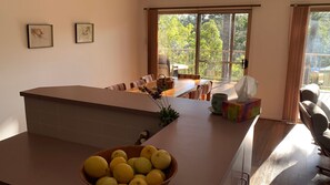 A kitchen with a dining area, a window with a view of trees, and a bowl of lemons on the counter.
