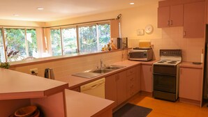 A kitchen with a sink, microwave, stove, and cabinets. - Leafy Long Beach Hideaway (LONG BEACH)