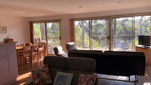 A living room with a sofa, a television, and a dining area with chairs and a table.