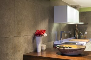 Un baño moderno con encimera de madera, un espejo grande, un lavabo y un florero con flores.