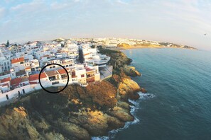 Un pueblo costero con edificios blancos, acantilados rocosos y una playa.