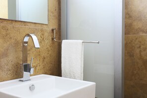 Un baño con lavamanos blanco, grifo de cromo y un perchero.