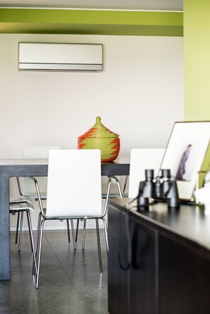 A modern dining area with a white table, metal chairs, and a decorative vase.