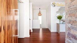 A hallway with wooden flooring, a hanging light fixture, and a stone accent wall. - Luxury in Corlette - 4 Drungall Ave - Beautiful Home with Air Con and WiFi (CORLETTE)