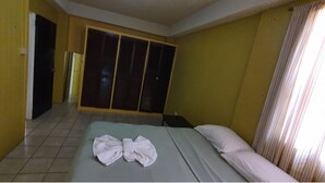Habitación de hotel con cama, armario y baño a la vista.