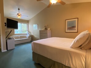 A bedroom with a bed, a television, a sofa, and a ceiling fan. - Mountain Harbor #205 3 Bedroom Condo (Whitefish)