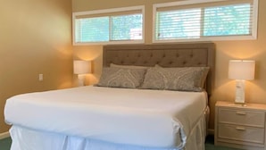 A bedroom with a large bed, two bedside tables with lamps, and a ceiling fan. - Mountain Harbor #205 3 Bedroom Condo (Whitefish)