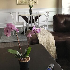 Relax in this inviting living space with a comfortable sofa, dining area, and a beautiful orchid.