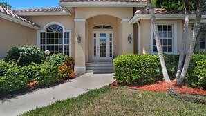 A two-story house with a beige facade, a tiled roof, and a front entrance with a set of stairs. - Family Friendly perfect place to make memories! (Marco Island)