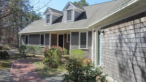 Ein zweistöckiges Haus mit überdachter Veranda und Garage.