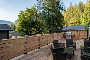 A wooden deck with outdoor furniture, a barbecue grill, and a view of a forested area. - C&C Home -Rural, Private, Fire Place, Quality (Nelson)