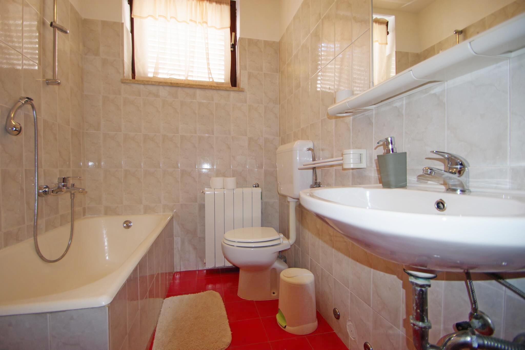 A bathroom with a bathtub, toilet, sink, and a window with curtains.