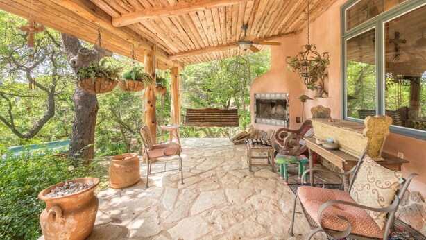 Un plafond en bois rustique, un revêtement de sol en pierre et une cheminée en pierre agrémentée d’un banc et d’une table.