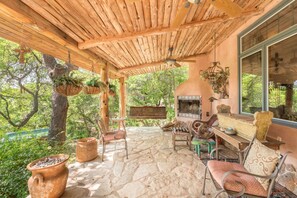 Un plafond en bois rustique, un revêtement de sol en pierre et une cheminée en pierre agrémentée d’un banc et d’une table.
