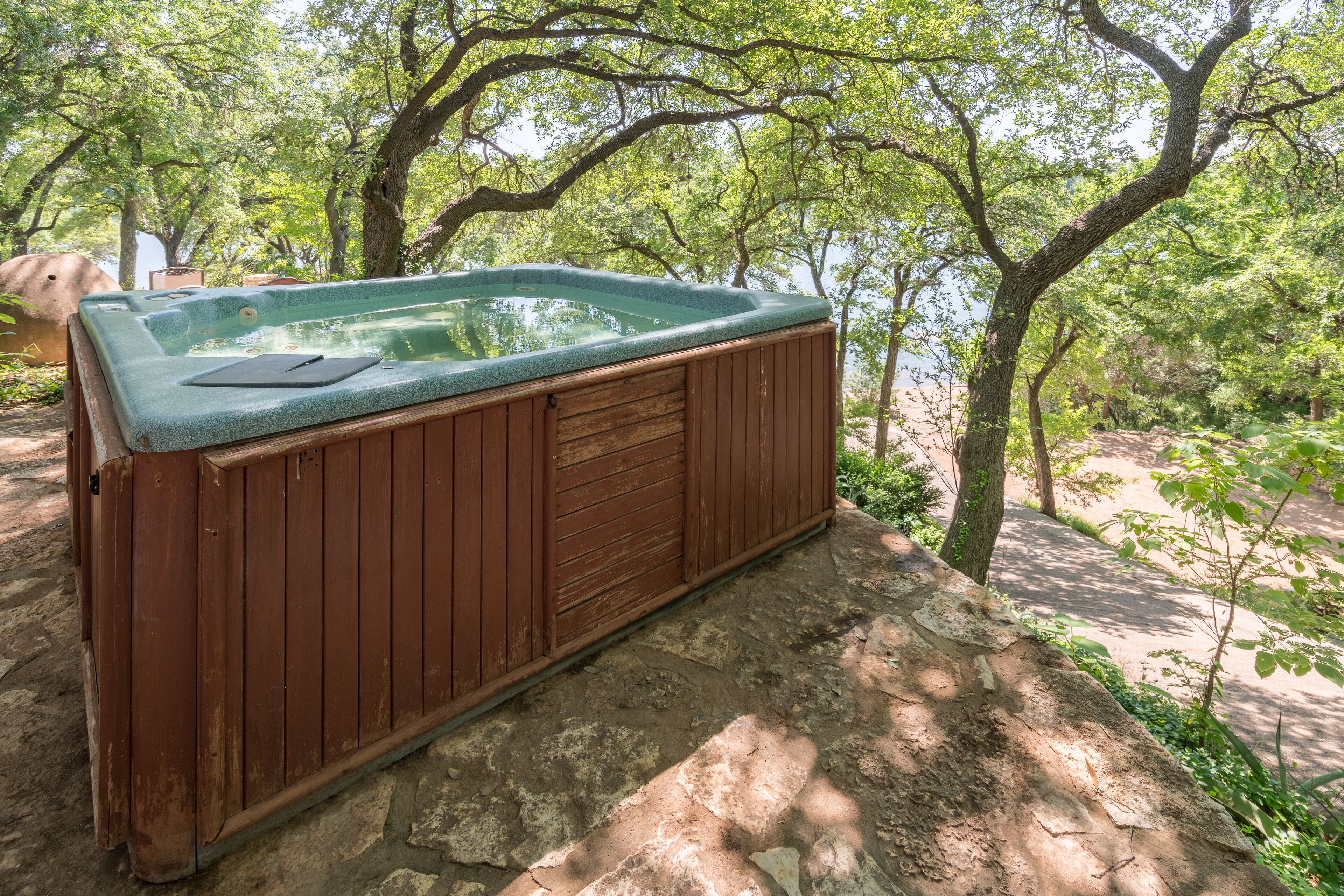 A hot tub in a wooded area with a stone floor.