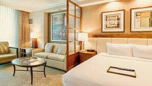 Une chambre d’hôtel avec un grand lit, un canapé, une petite table et une fenêtre avec des rideaux.