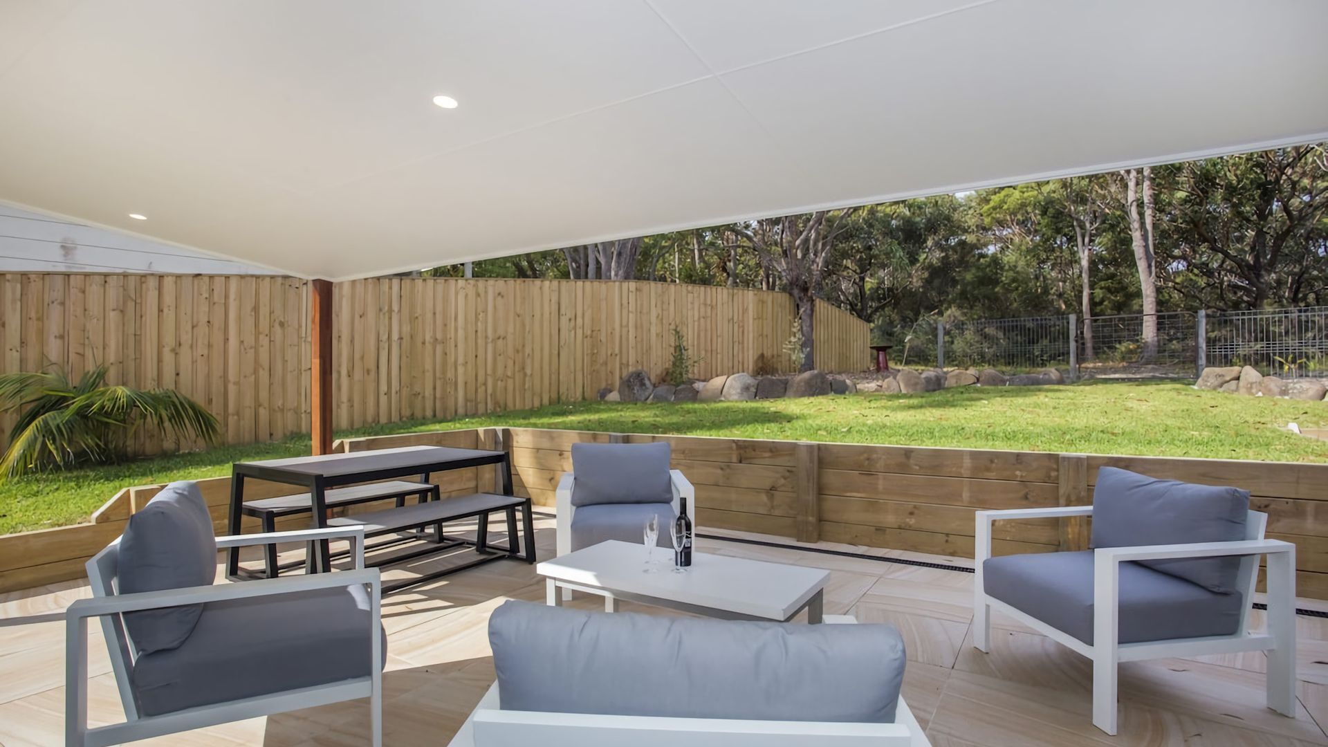 Un espace extérieur aménagé en terrasse, avec une plateforme en bois, une table entourée de chaises et un canapé.