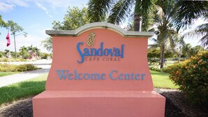 A Welcome Center sign with the text "Sandoval Cape Coral" and a pineapple logo. - 3BR villa in gated community w/tons of amenities! Villa Eleadora - SWFL Rentals (Cape Coral)