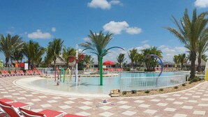 A pool area with red and white sun loungers, palm trees, and a clear blue sky. - 3BR villa in gated community w/tons of amenities! Villa Eleadora - SWFL Rentals (Cape Coral)