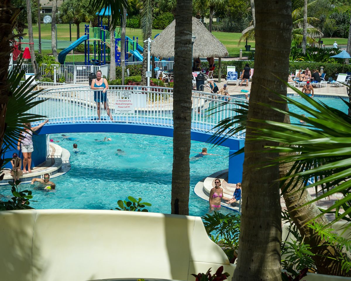 A swimming pool area with a slide, lounge chairs, and a play structure.