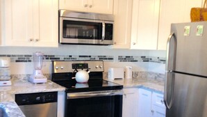 A modern kitchen with white cabinets, stainless steel appliances, and a marble countertop. - 2nd floor of duplex. Bay view, sunsets, beach, activities. Great family getaway! (Ship Bottom)