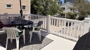 A balcony with a table, chairs, and a red umbrella. - 2nd floor of duplex. Bay view, sunsets, beach, activities. Great family getaway! (Ship Bottom)