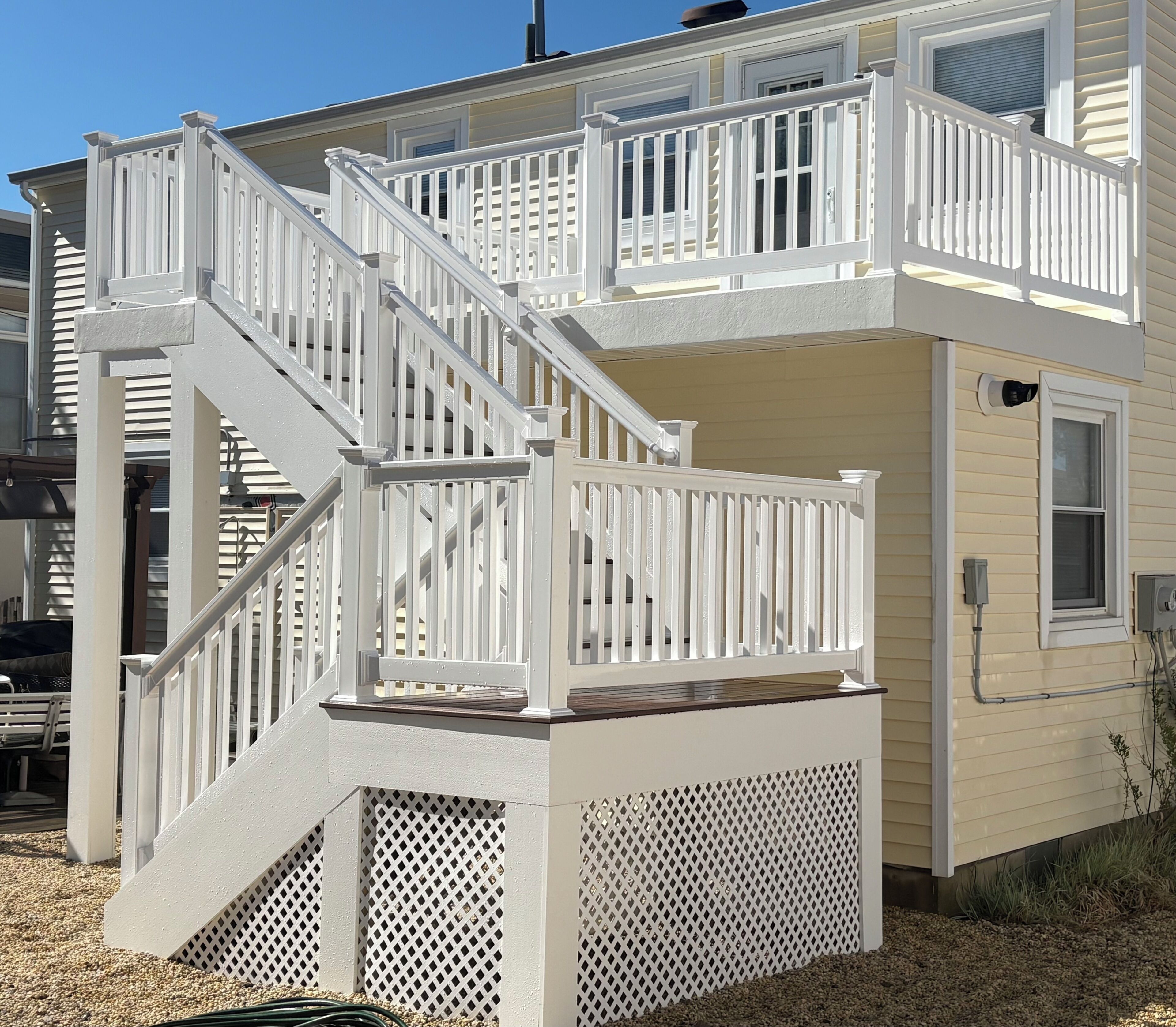 A two-story building with a white exterior, a balcony on the upper floor, and a staircase leading to the second floor.